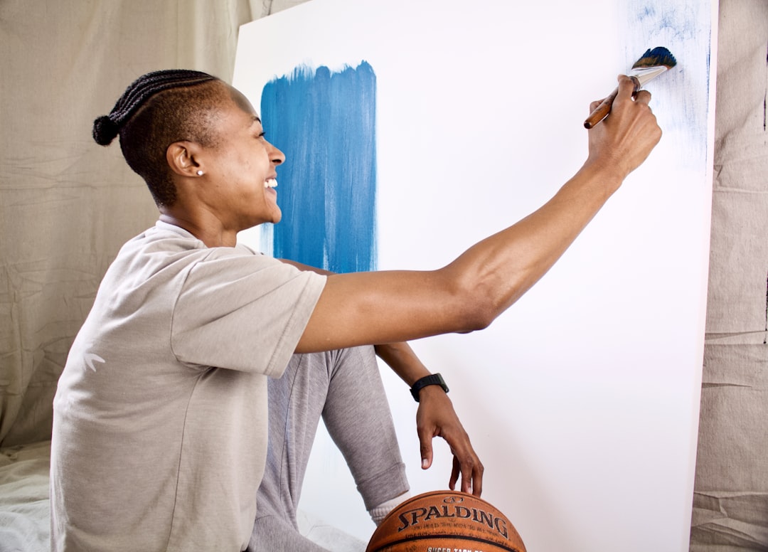 man in gray polo shirt holding brown wooden basketball