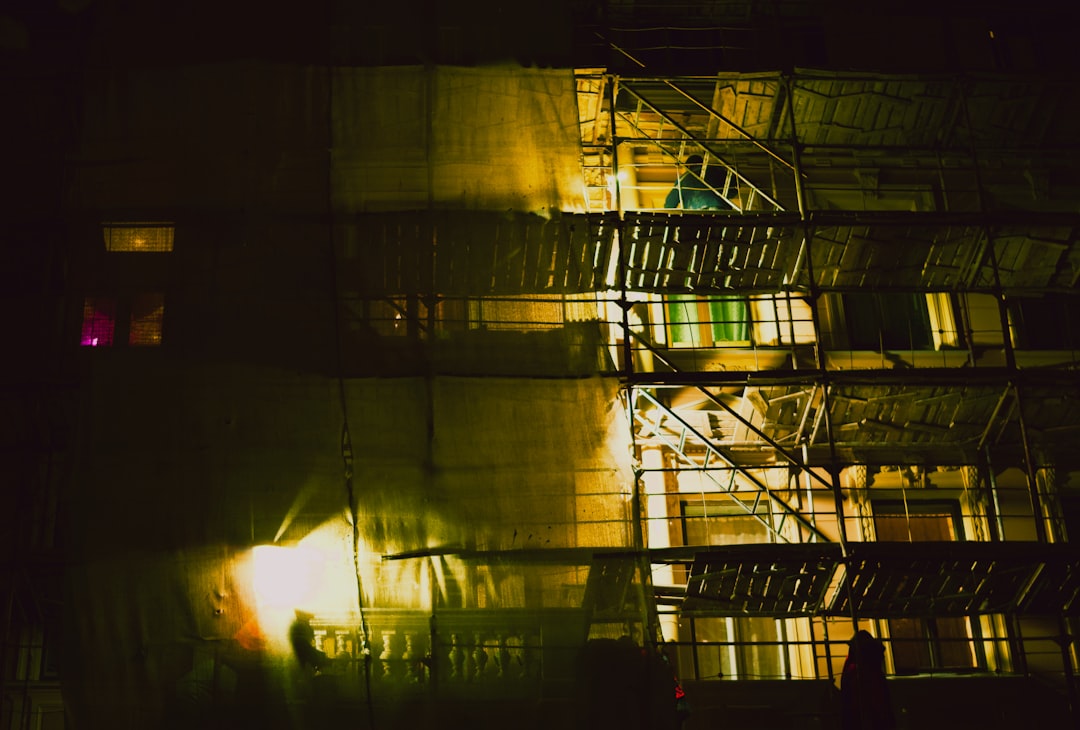 Building exterior at night with scaffolding and lights