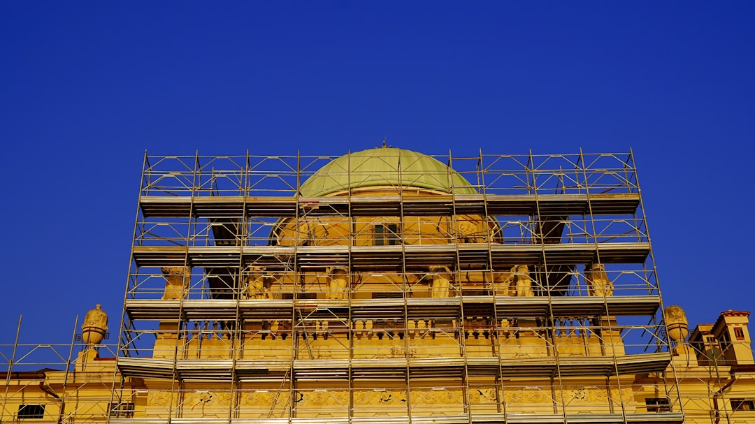 Building dome covered in scaffolding under blue sky