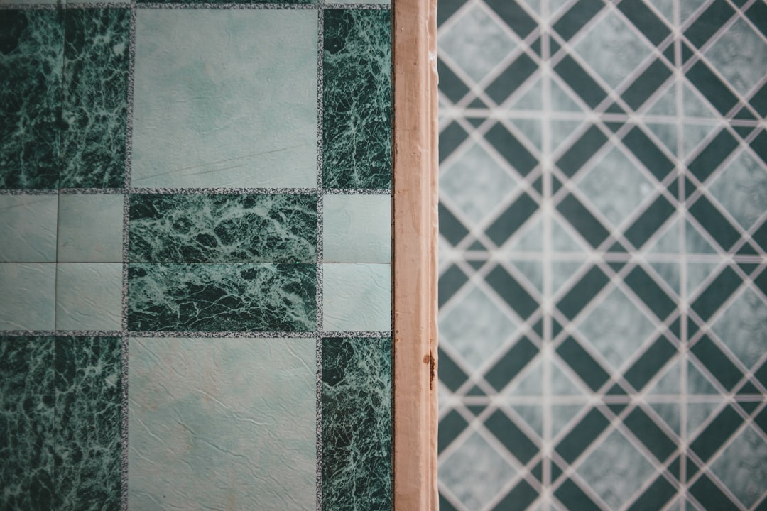 a green and white tiled bathroom with a wooden door