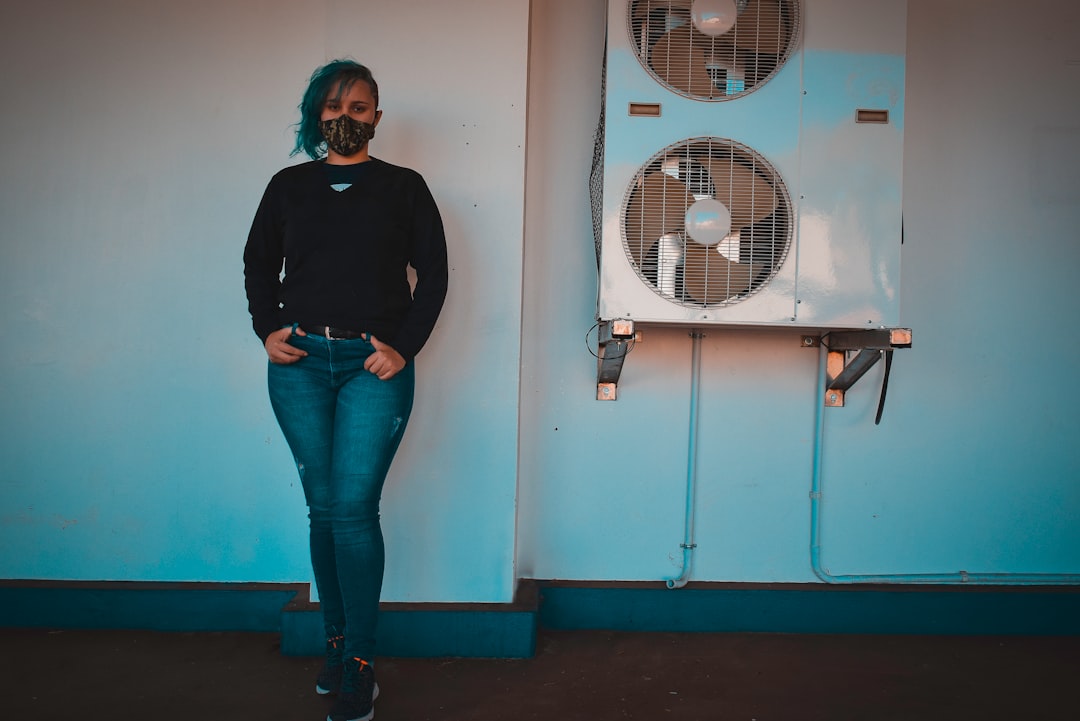 woman in black long sleeve shirt and blue denim jeans standing beside white wall