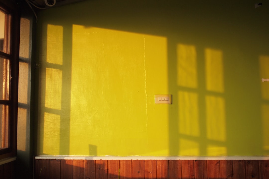 brown wooden bench beside yellow wall
